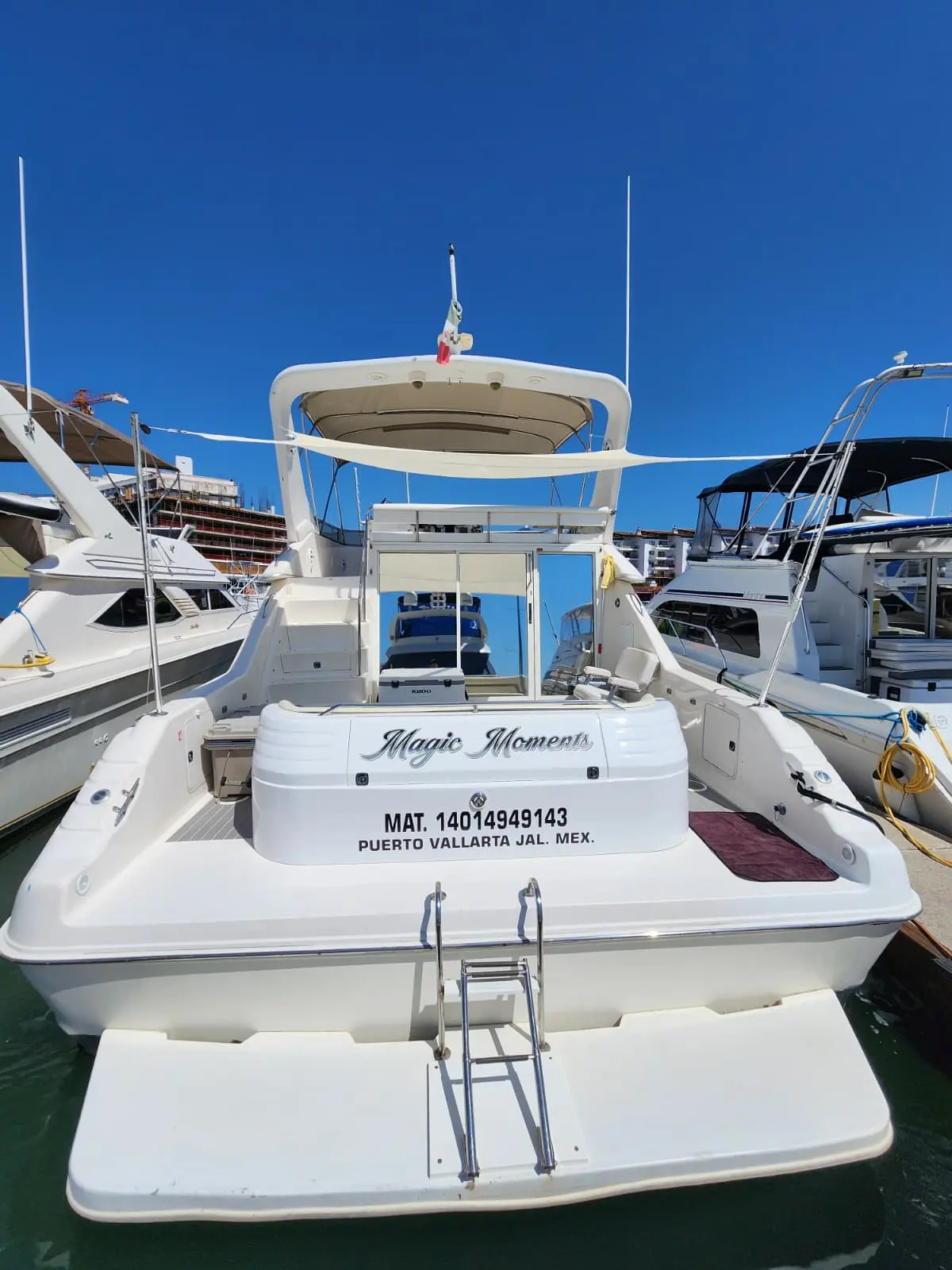 Stern of the motor yacht with its swim platform and ladder, moored among boats in the marina