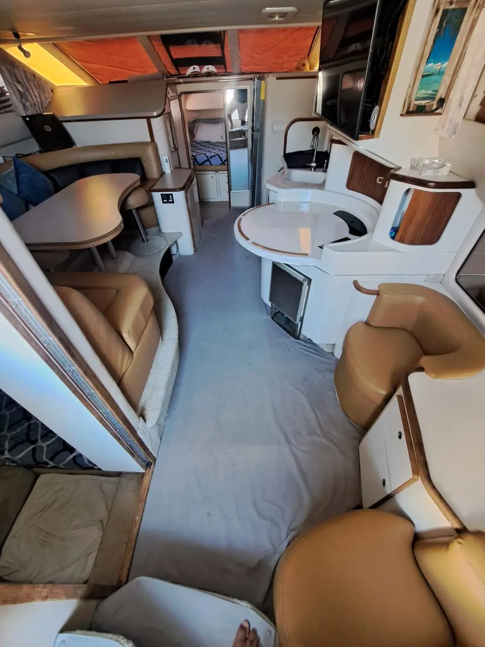 Below-deck salon of the yacht with tan leather seating, dinette tables and a galley counter