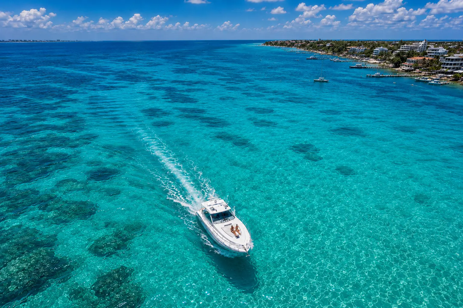 Aerial view of a motor yacht speeding over turquoise reef waters along the coast near Cancún