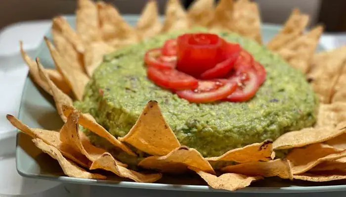 Guacamole topped with a tomato rose and ringed with tortilla chips