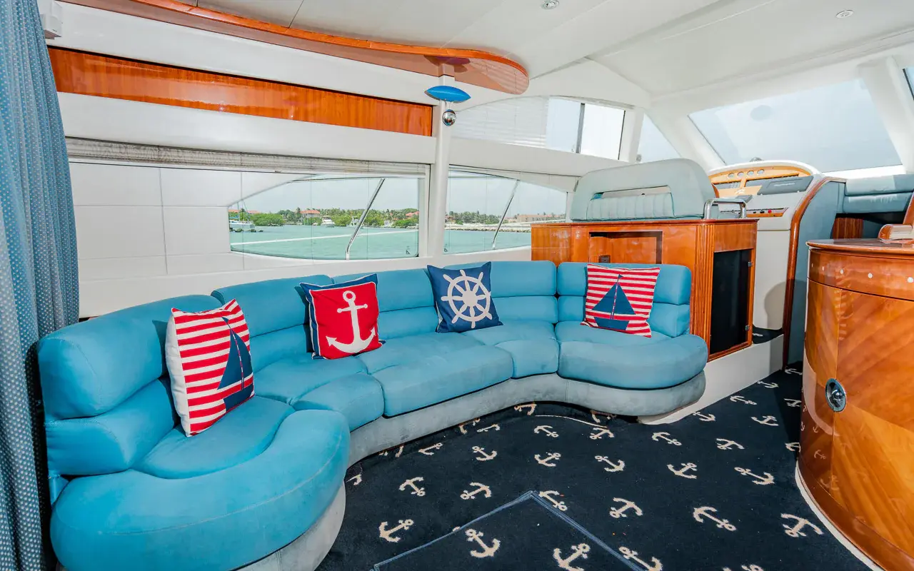 Yacht salon with a curved turquoise sofa, nautical pillows and anchor-print carpet