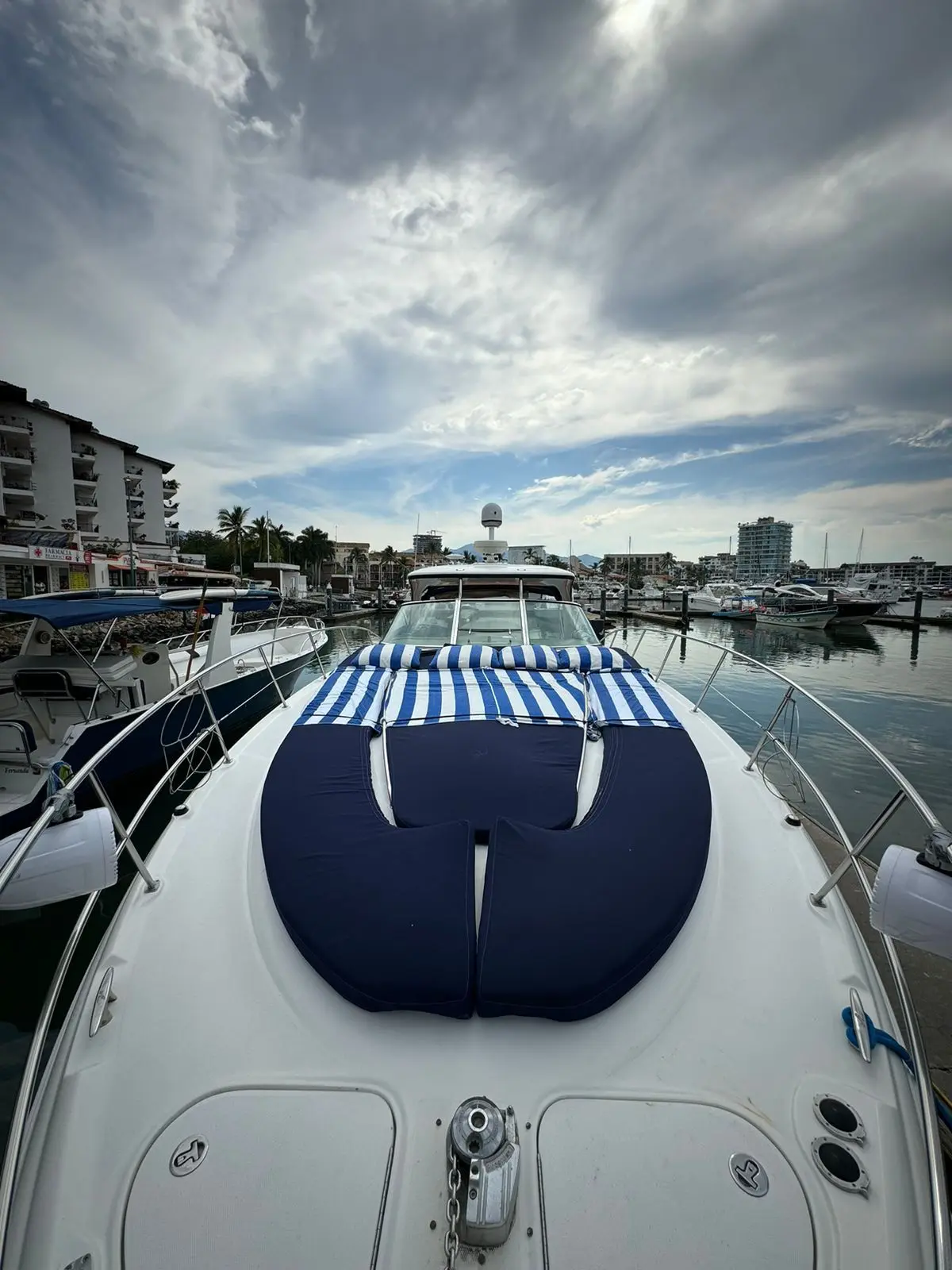 Navy sunpad and striped towel on the yacht's foredeck, docked in the Puerto Vallarta marina