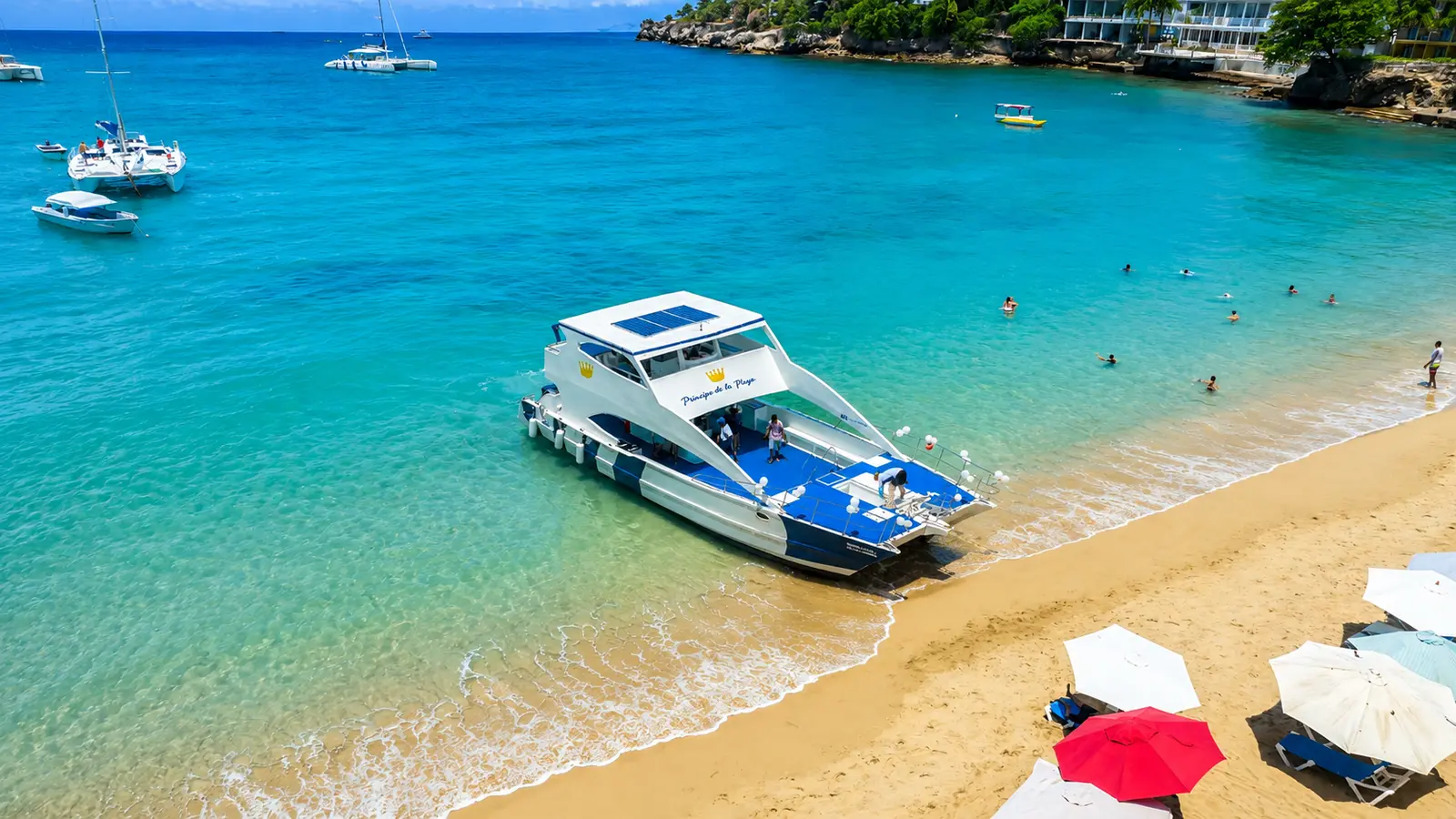 Power catamaran moored at a golden sand beach near Puerto Plata, with umbrellas ashore and swimmers in the bay