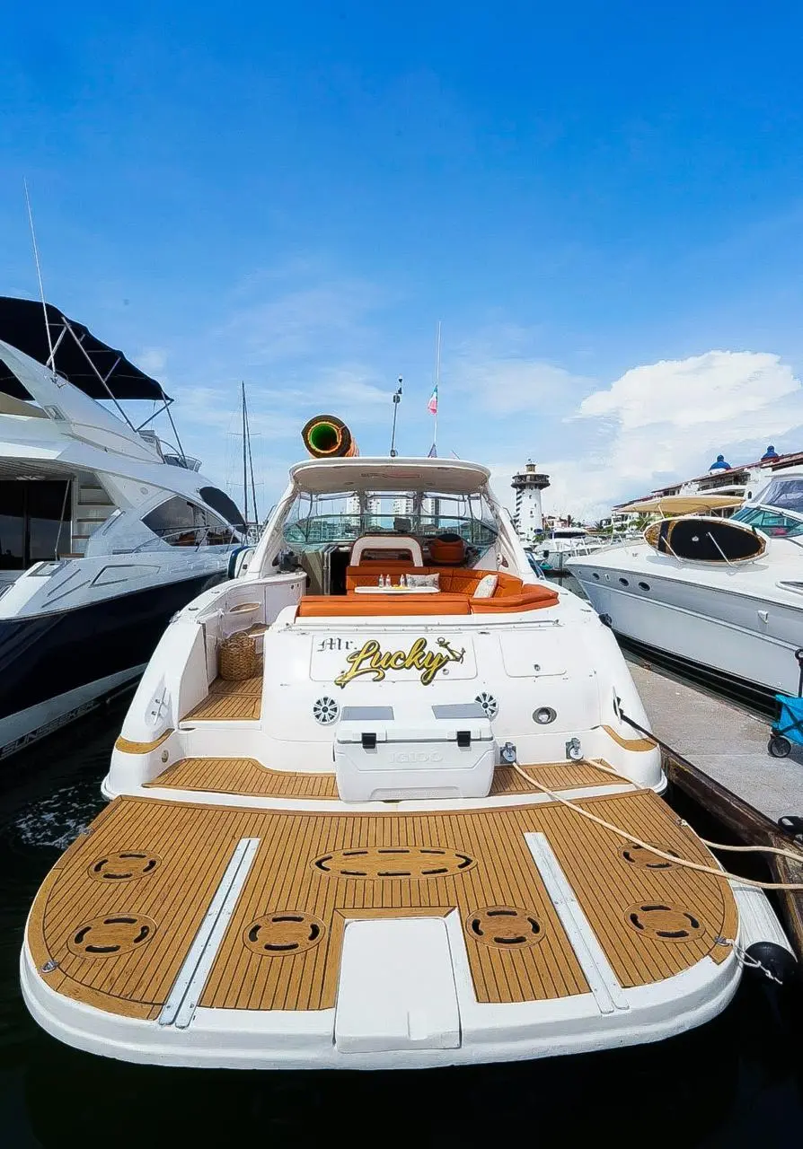 Stern of the motor yacht with a teak swim platform, docked between other yachts in the Puerto Vallarta marina