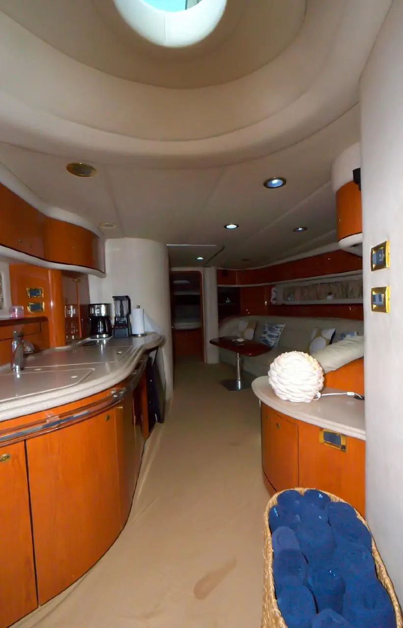 Yacht galley and salon with curved counters, cherry wood cabinets and a round skylight