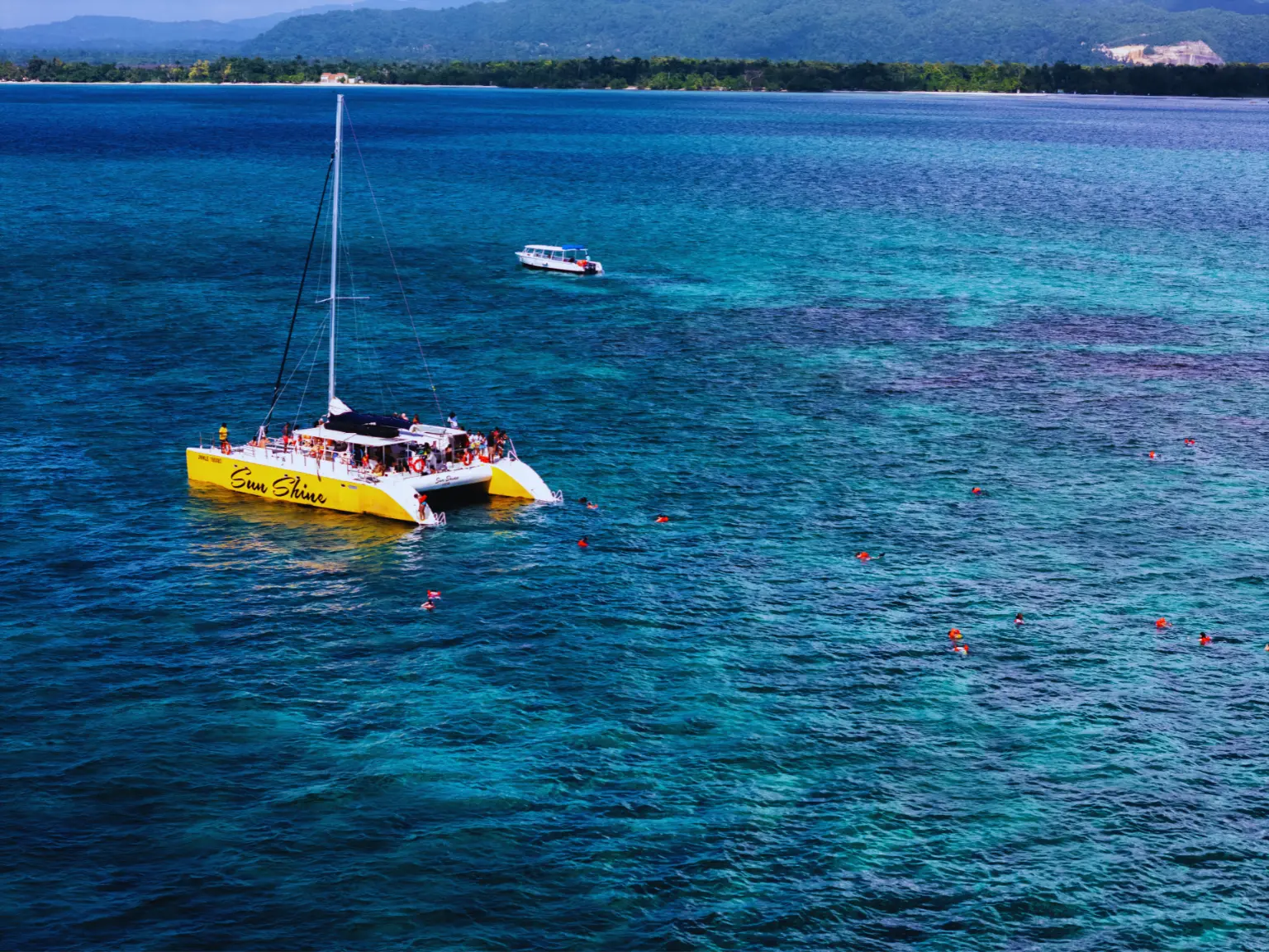 Yellow catamaran with swimmers in clear water off Negril, Jamaica