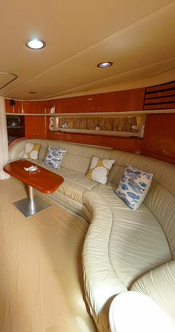The yacht's below-deck lounge with a curved cream leather sofa, wood paneling and a small table