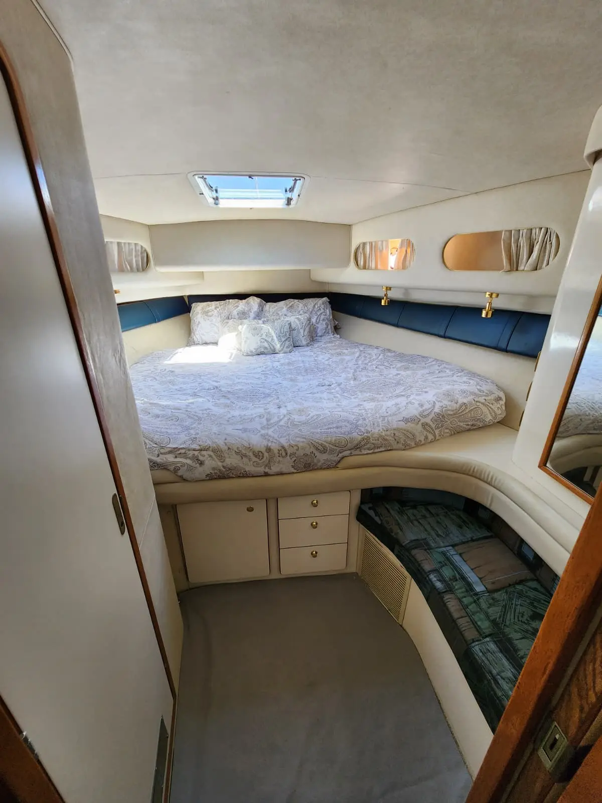 Forward cabin with a double bed, overhead hatch and built-in drawers aboard the yacht