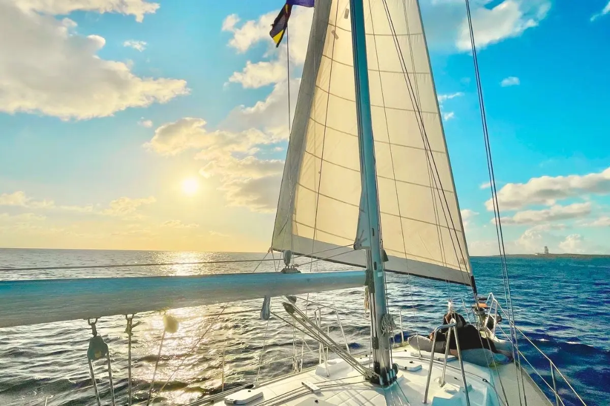 Low sun shining past the full sails of a sailing yacht cruising off Curaçao