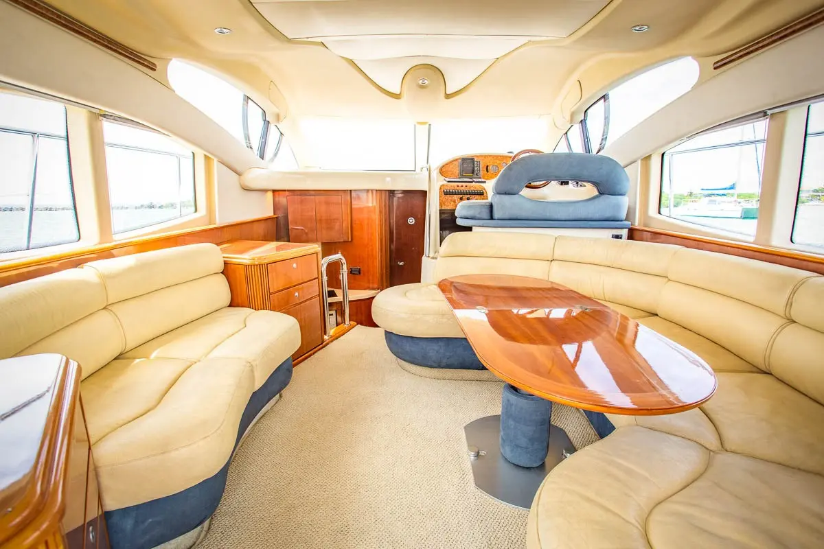 Yacht salon with cream leather sofas, a glossy wooden table and the lower helm forward