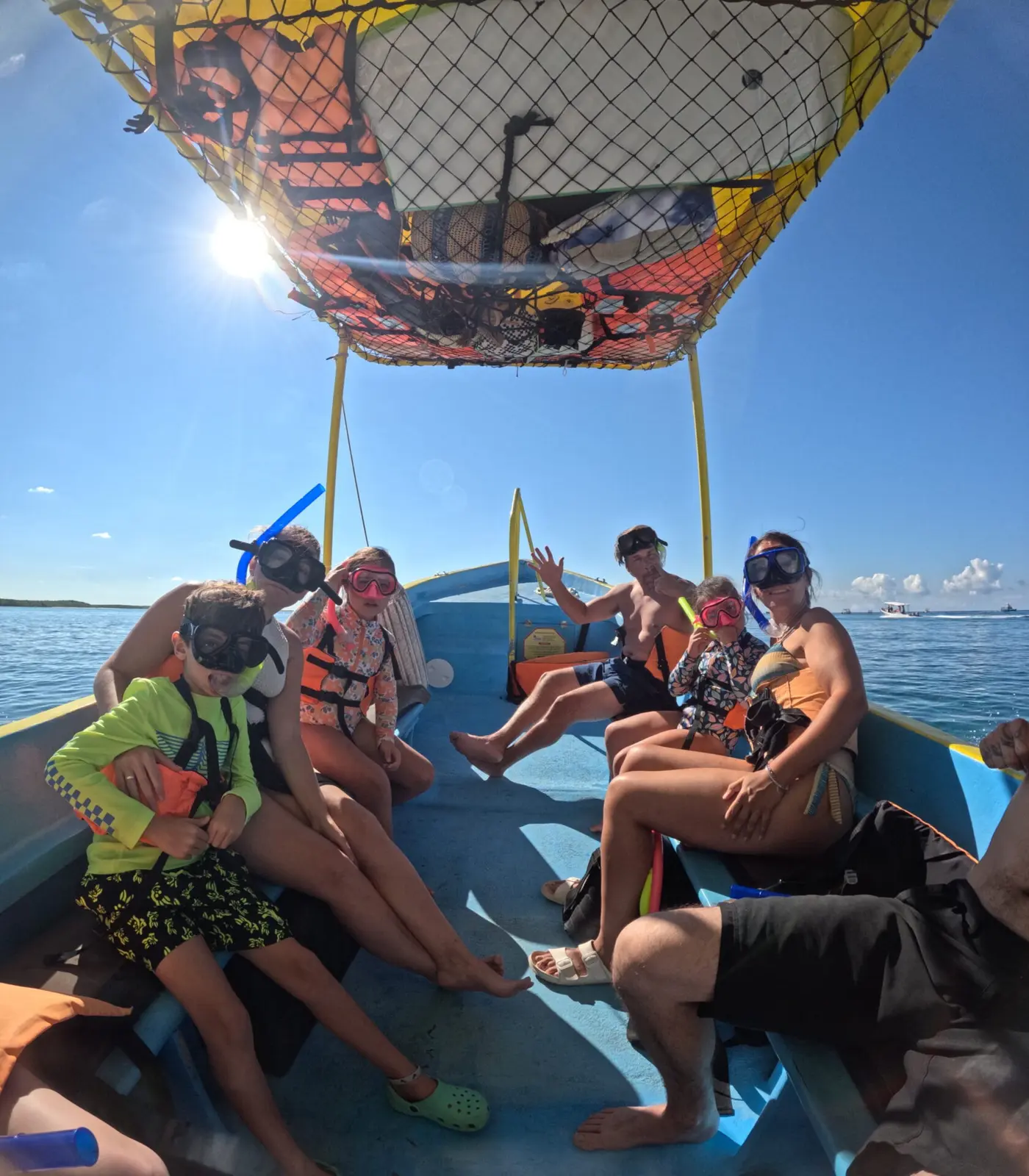 Group in snorkel masks and life vests riding under the speedboat's shade canopy off Cozumel