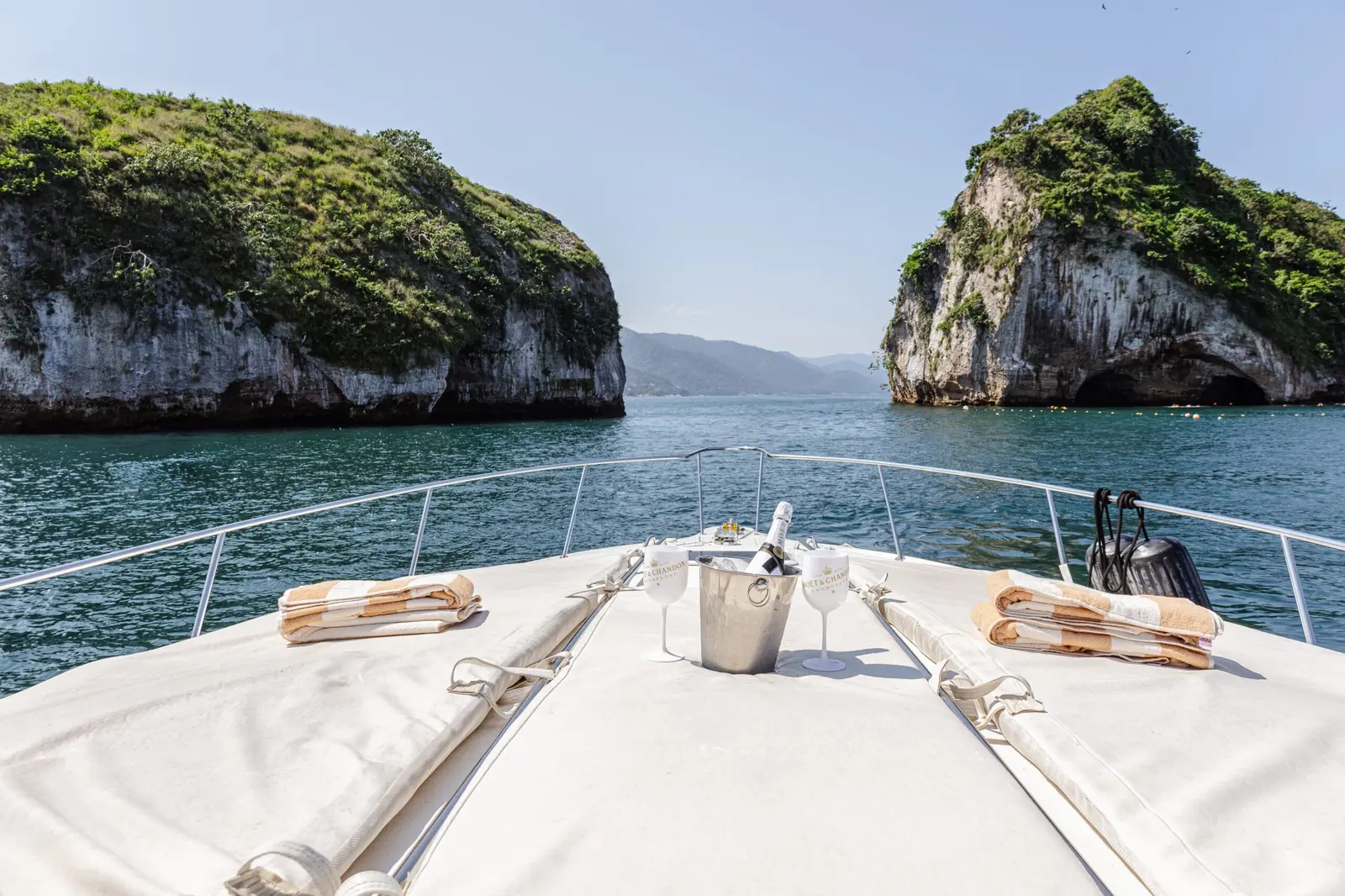 View from the yacht's bow, with rolled towels and an ice bucket, toward the rock islands of Los Arcos