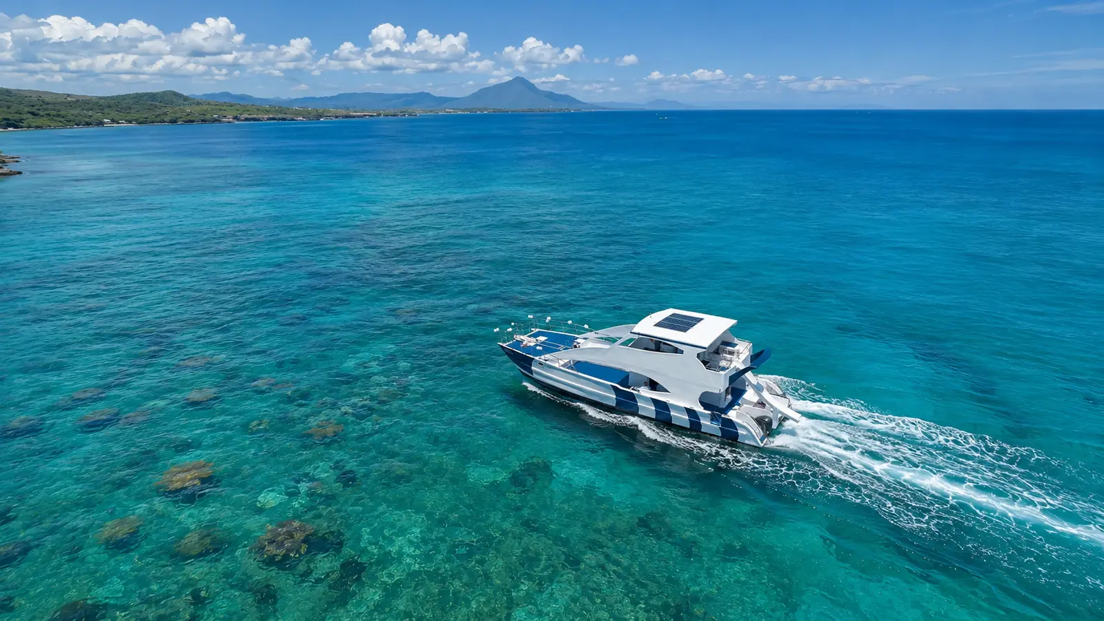 Aerial view of a catamaran speeding over reef-dotted turquoise water off Puerto Plata