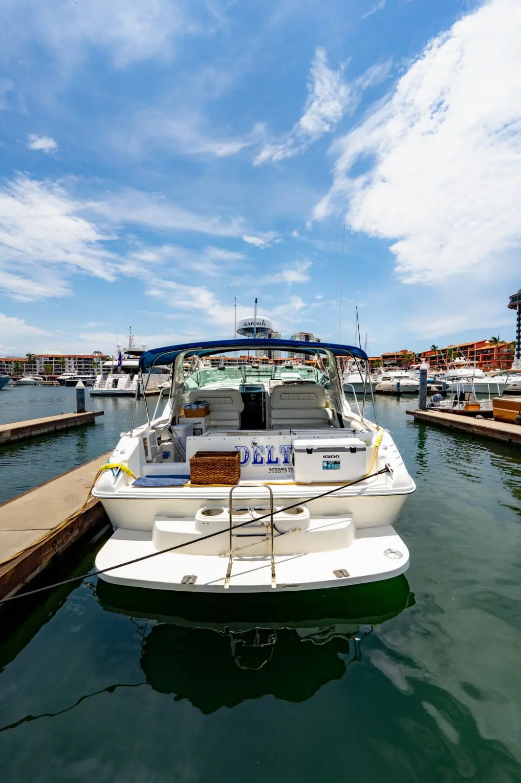 A motor yacht moored in its slip at a Puerto Vallarta marina under puffy white clouds