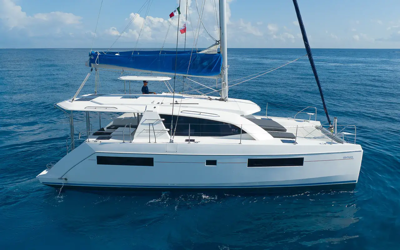 Sailing catamaran with its mainsail stowed on deep blue water off the Riviera Maya