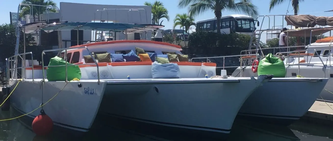 Trimaran docked at the marina with colorful cushions and green bean bags along its deck