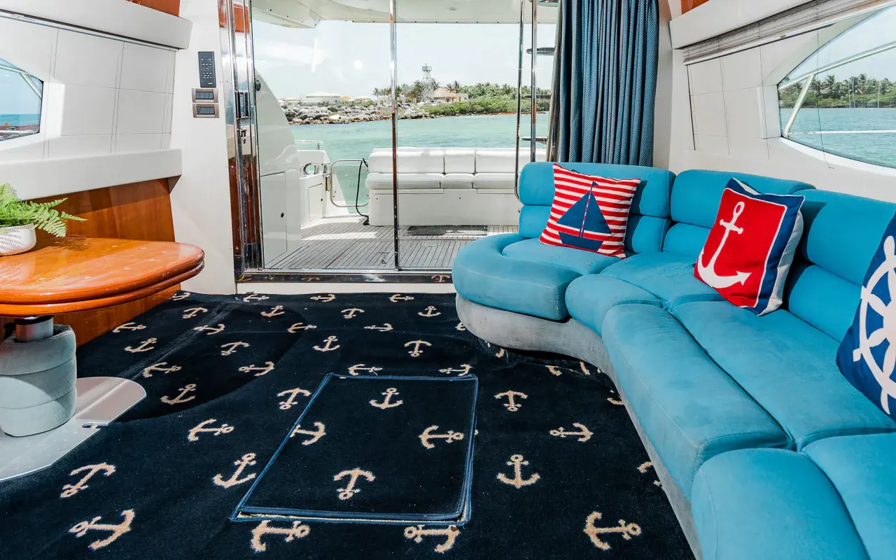Turquoise salon sofa beside open glass doors leading out to the aft deck and water