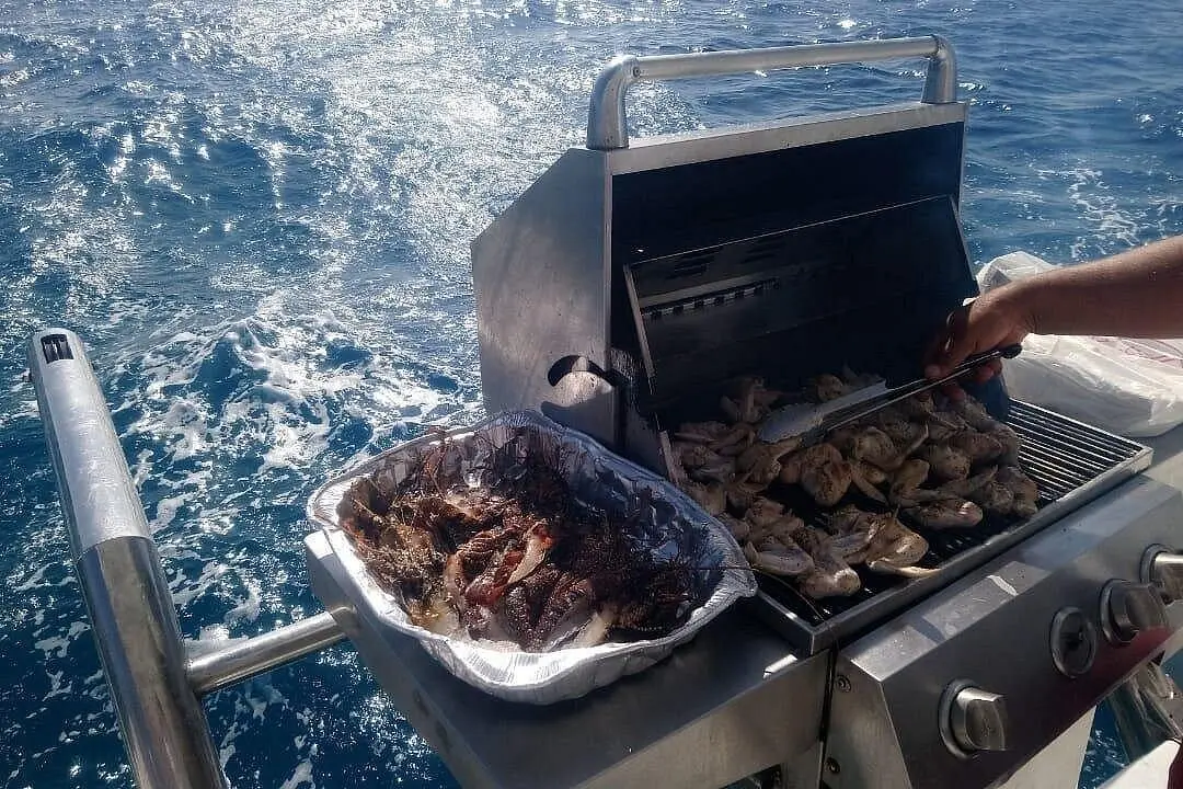 Lobster and chicken sizzling on a stainless steel grill on the catamaran's stern rail