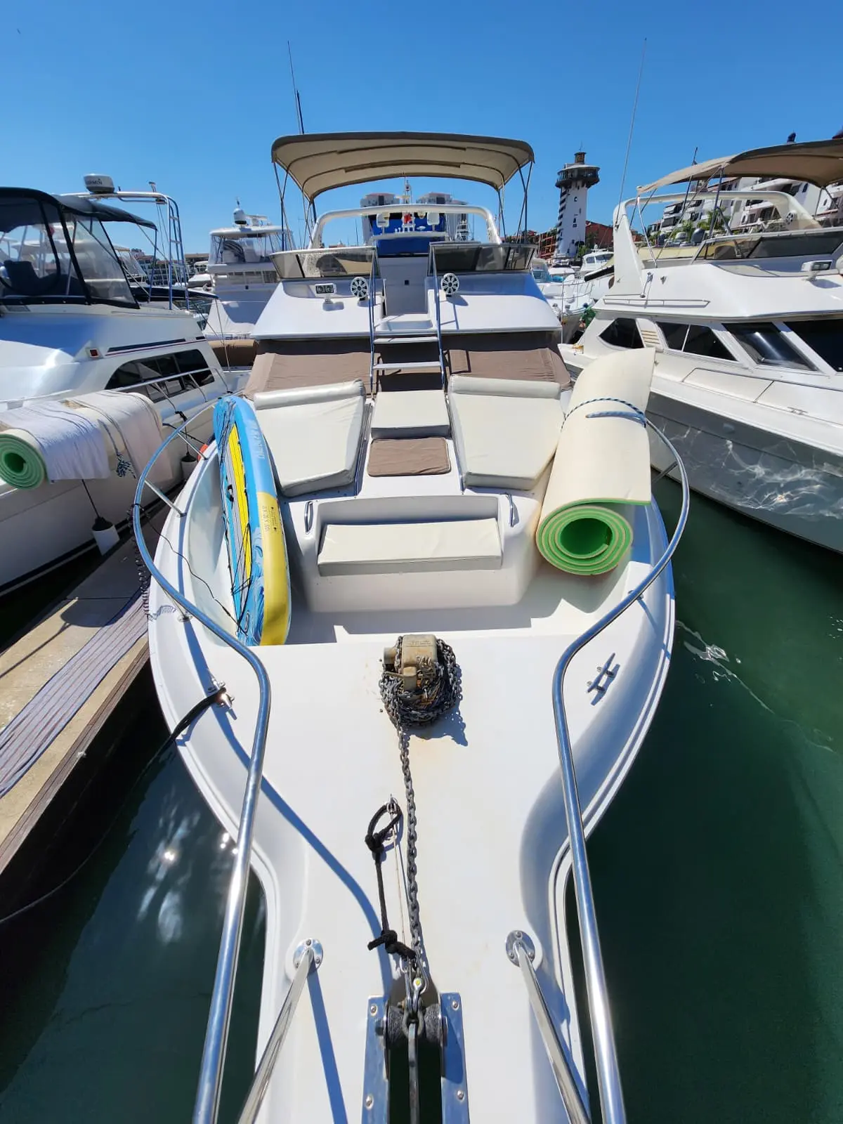 Paddleboards and a rolled water mat stowed on the yacht's foredeck while docked in the marina