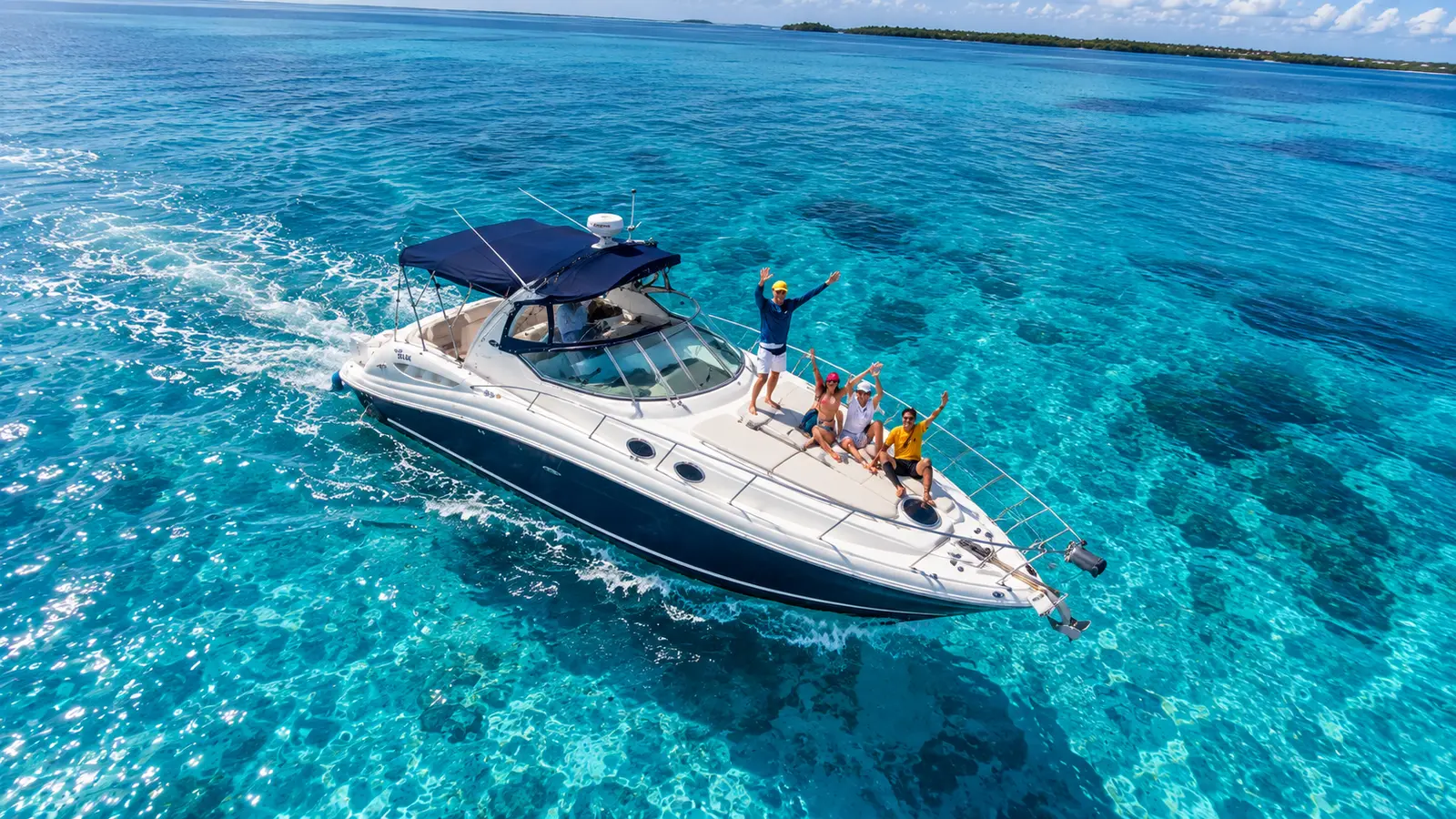 Private yacht cruising turquoise water off Cancún with guests on the bow