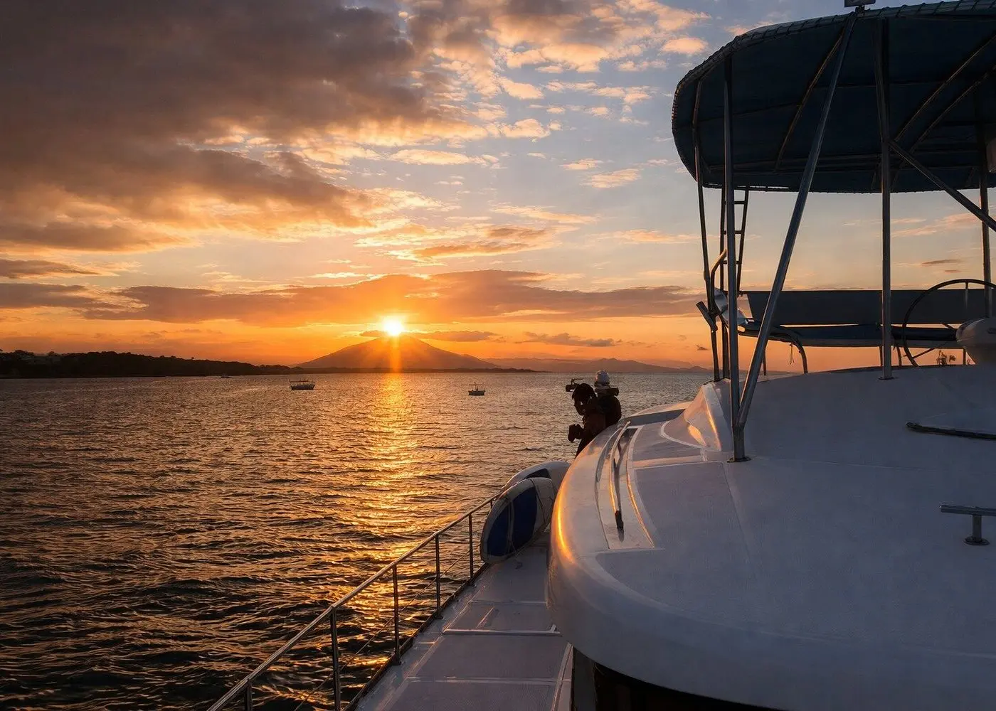 Sun setting behind distant hills off Puerto Plata, seen from the side deck of a catamaran