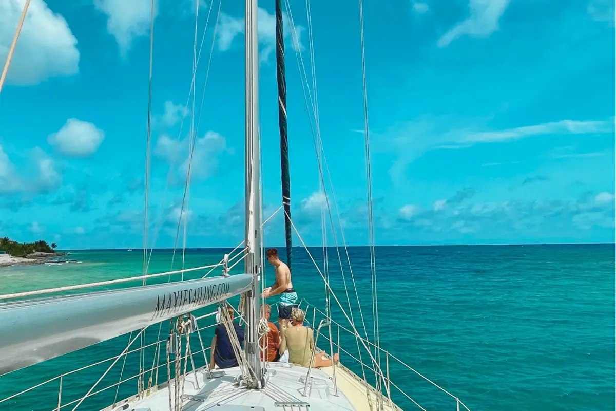 Guests gathered at the bow as the sailing yacht heads out over turquoise water off Curaçao
