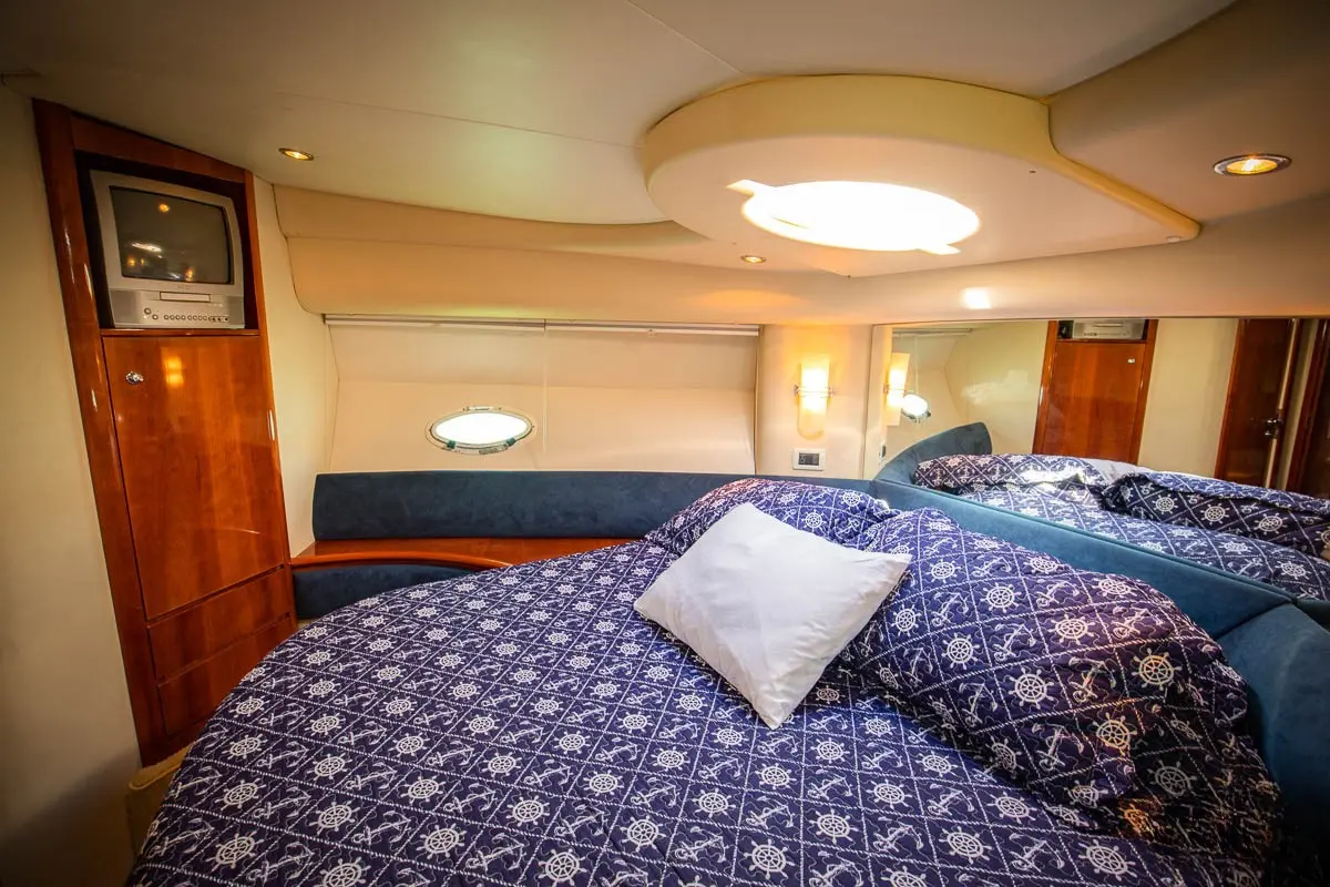 Cabin with a double bed in a blue patterned spread, wood trim and an overhead skylight