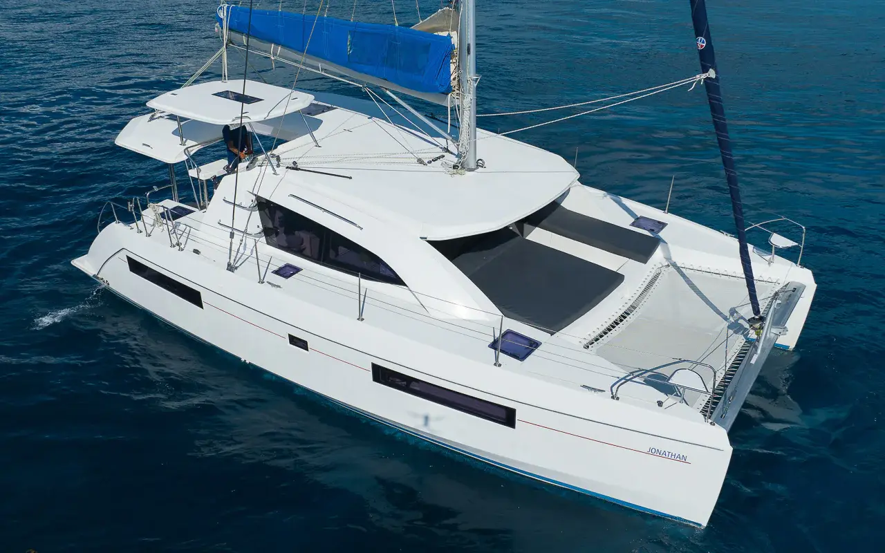 Aerial view of a sailing catamaran with a blue sail cover cruising deep blue water off the Riviera Maya