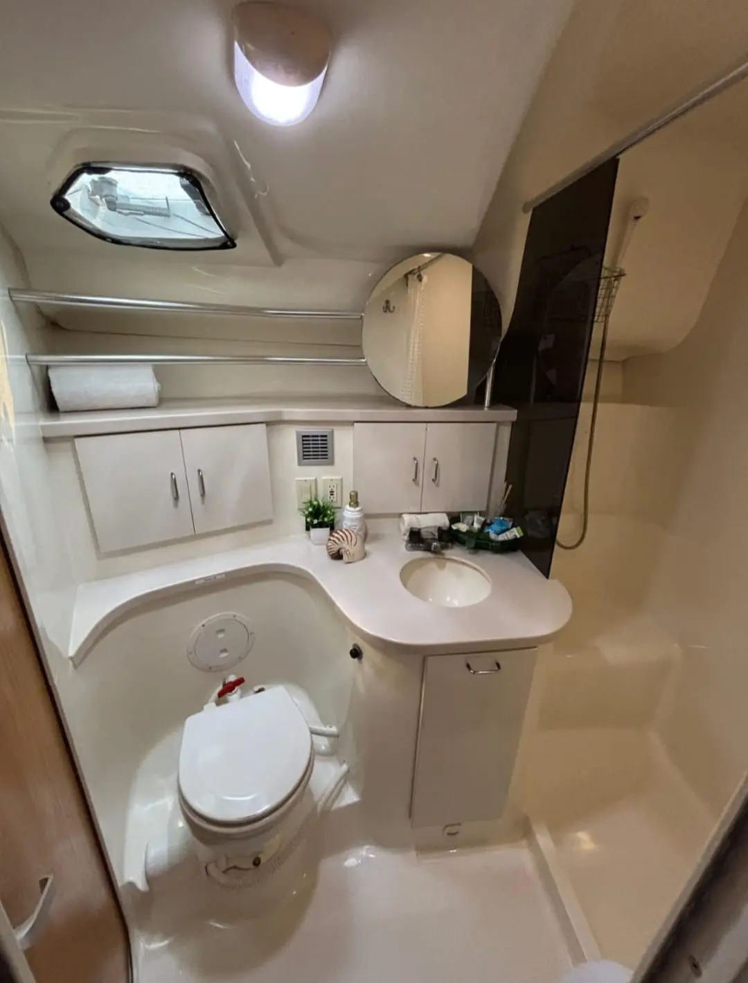 Yacht bathroom with a toilet, vanity sink, round mirror and porthole