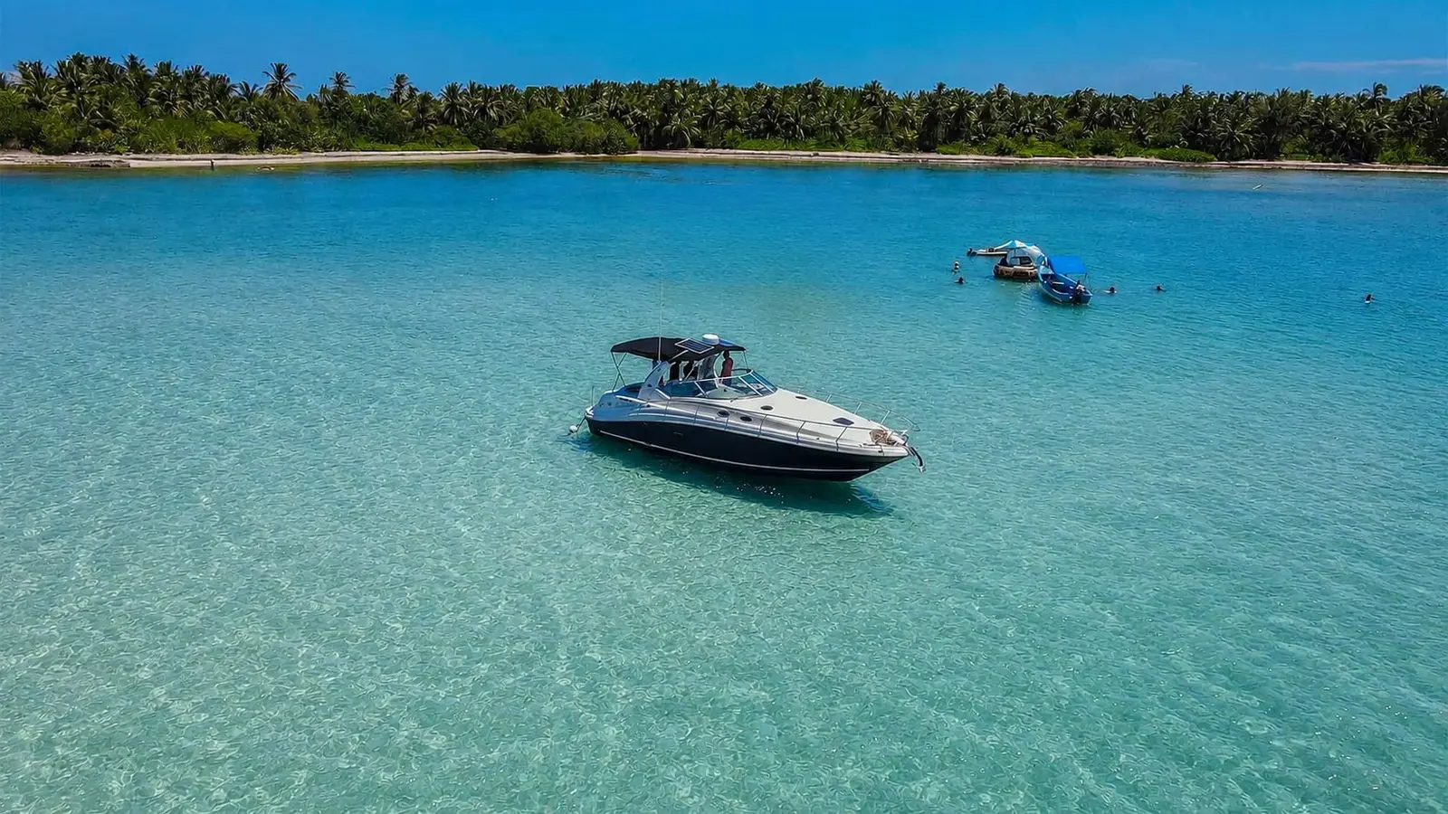 Yacht anchored in clear turquoise shallows off the palm-lined Punta Cana coast