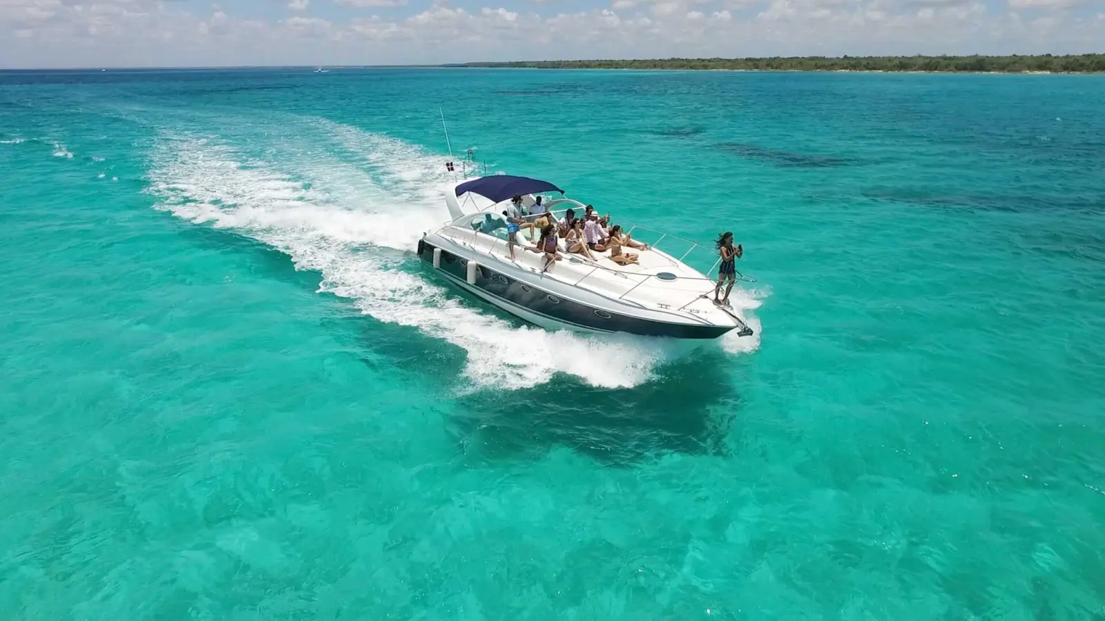 Aerial view of a yacht with guests on deck cruising through turquoise water off Punta Cana