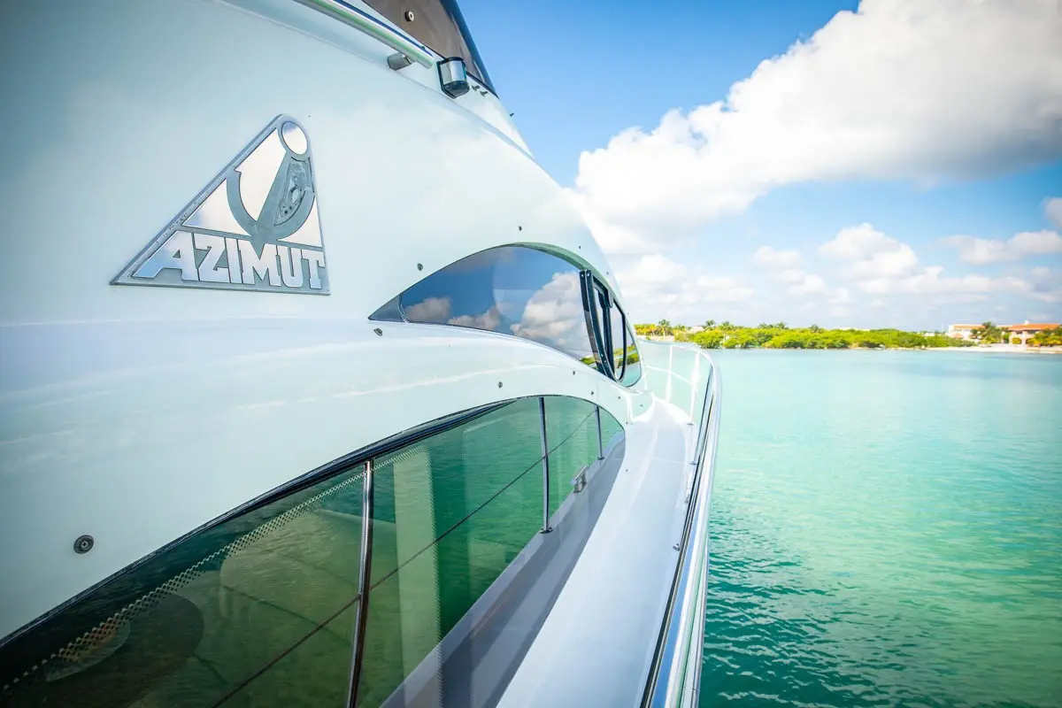 Azimut logo on the yacht's glossy white hull, with turquoise Riviera Maya water and shoreline beyond