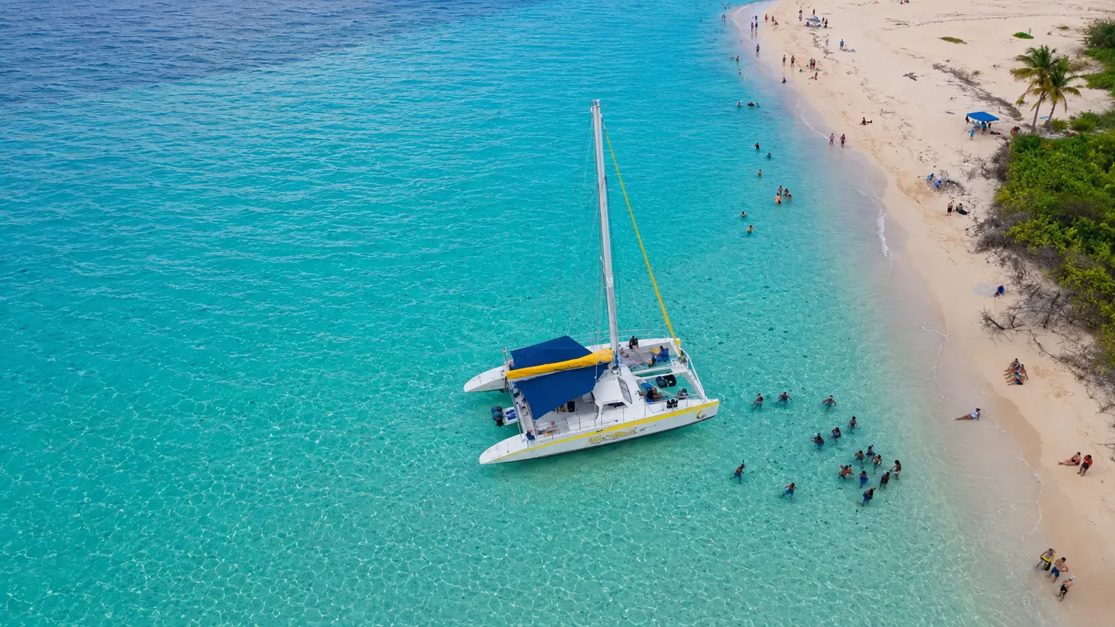 Sailing catamaran by a white-sand beach with swimmers near Fajardo, Puerto Rico