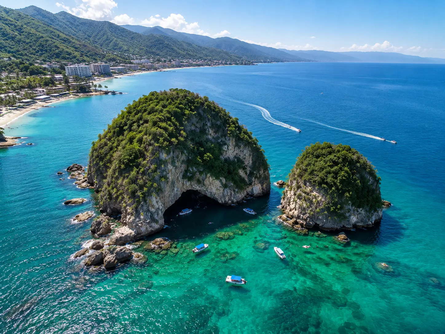 Aerial view of the Los Arcos rock formations rising from turquoise water with small boats moored around them