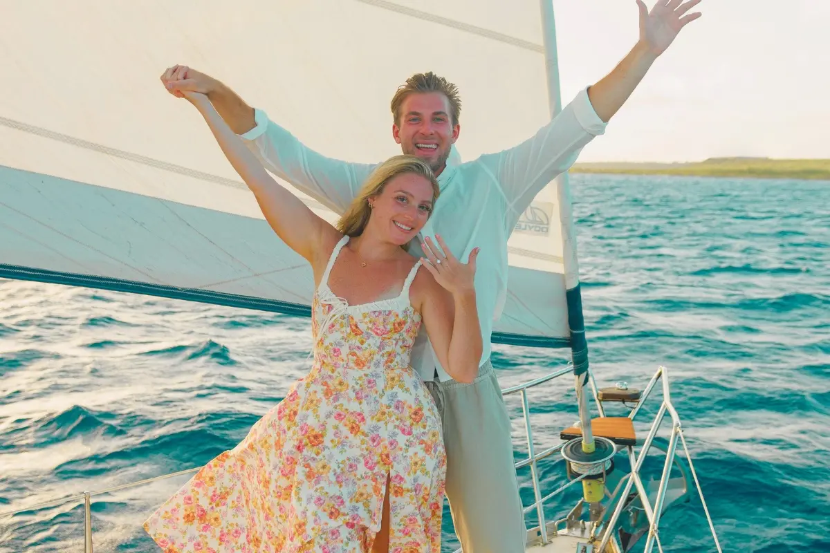 Couple celebrating with arms raised on the deck of a sailing yacht off Curaçao