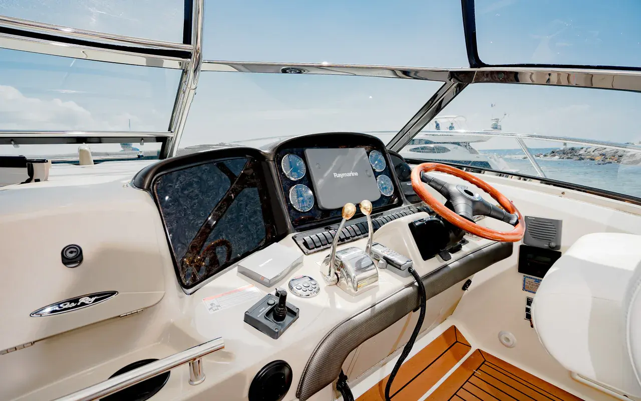 Yacht helm with a wood-rimmed steering wheel, digital gauges and throttles behind the windshield