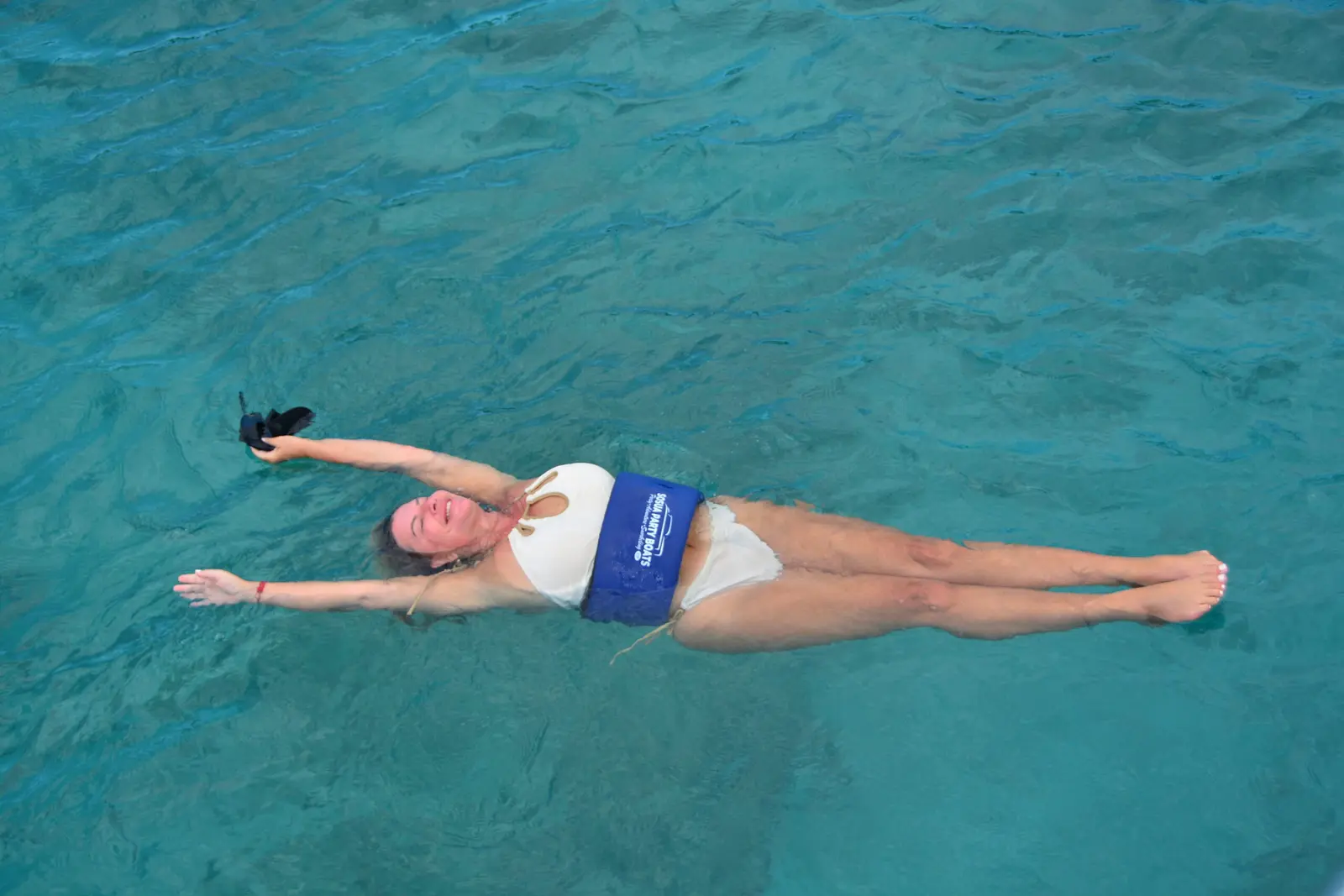 Woman floating on her back with arms spread in clear turquoise water