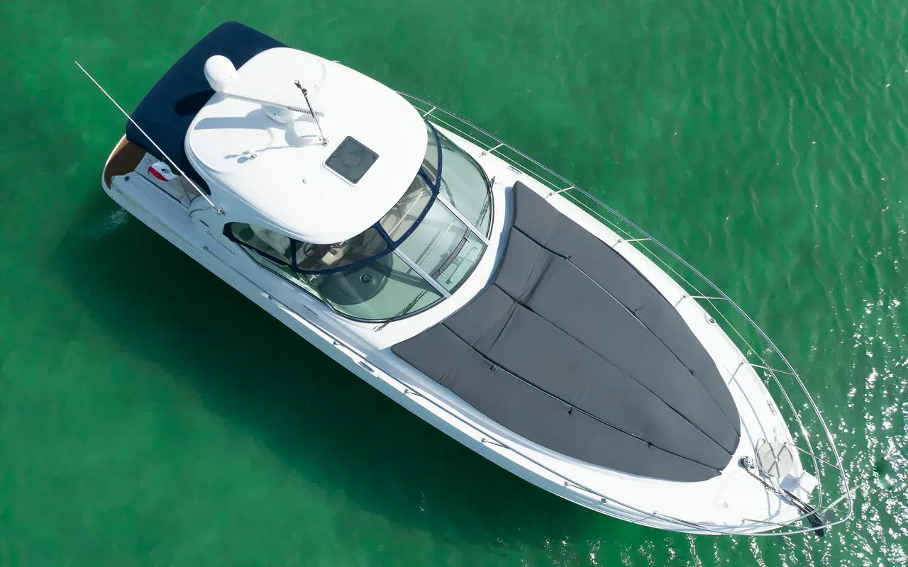 Overhead view of the motor yacht at rest on green water, gray bow sun pad and hardtop visible