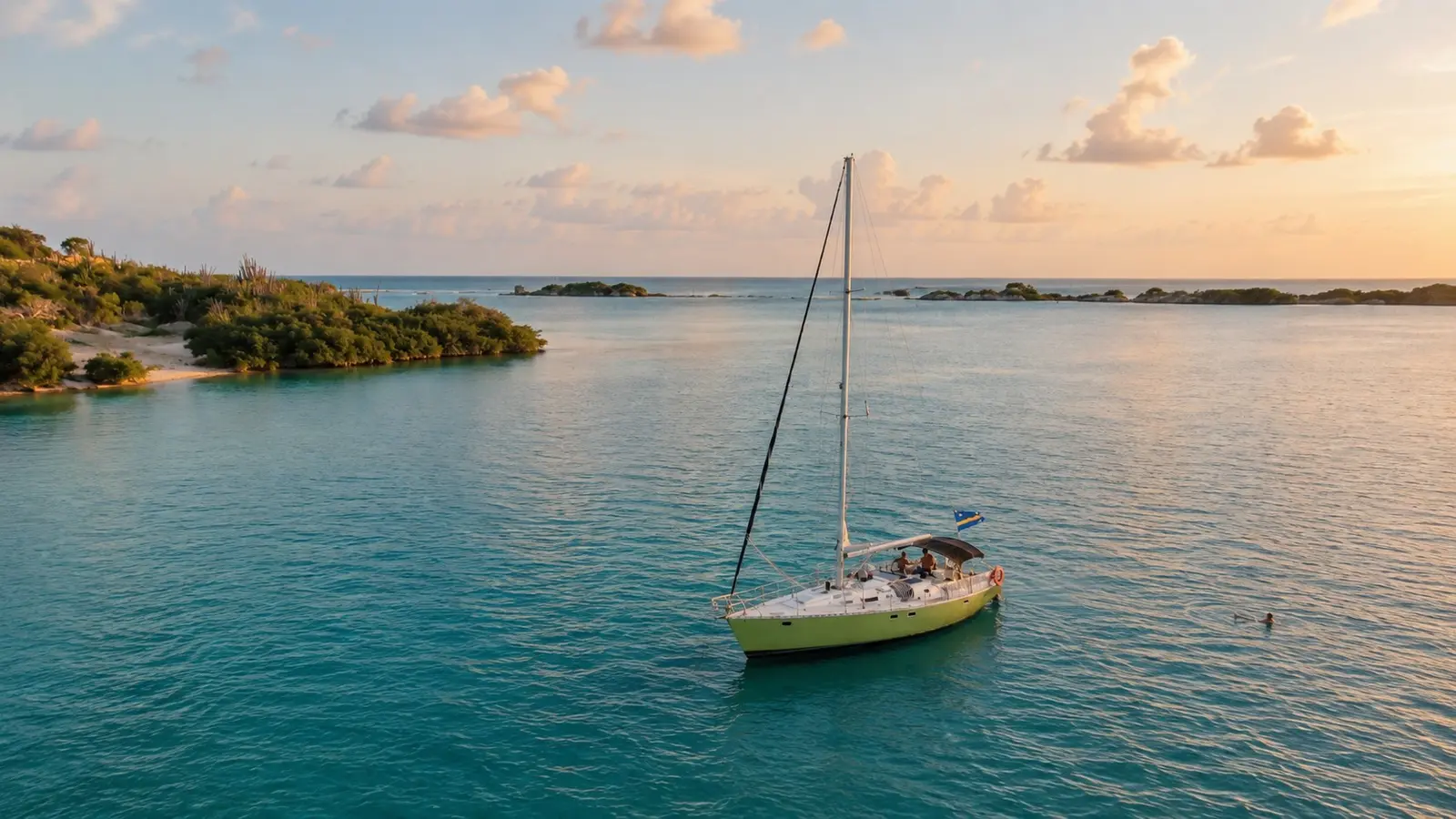 Sailing yacht anchored alone in a calm Curaçao bay beside a green headland at golden hour