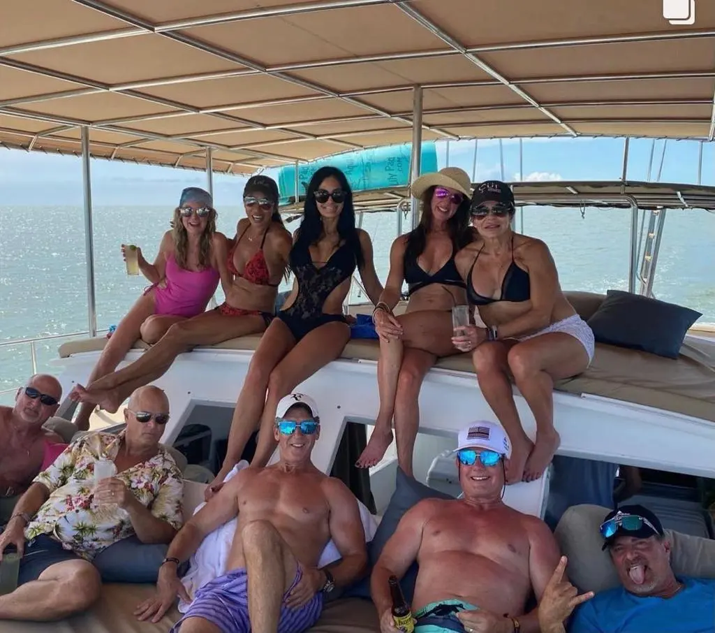Friends posing on deck under the canopy, women perched on the cabin roof and men lounging below