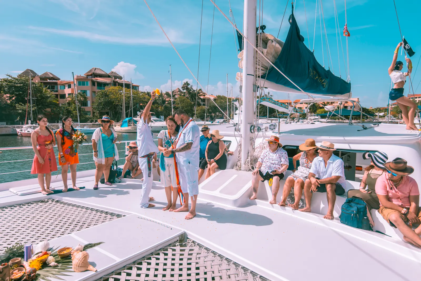 Wedding ceremony on the sailing catamaran's foredeck as guests look on, Puerto Aventuras marina behind