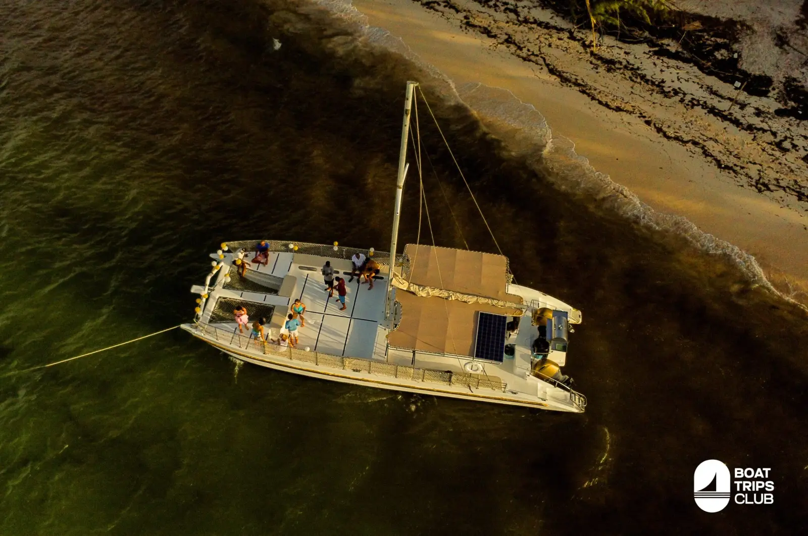 Aerial view of a sailing catamaran anchored near the Punta Cana shoreline in golden evening light