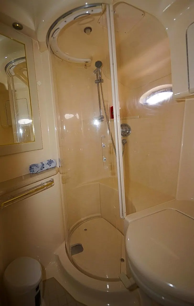 Yacht bathroom with a curved shower stall, toilet and porthole