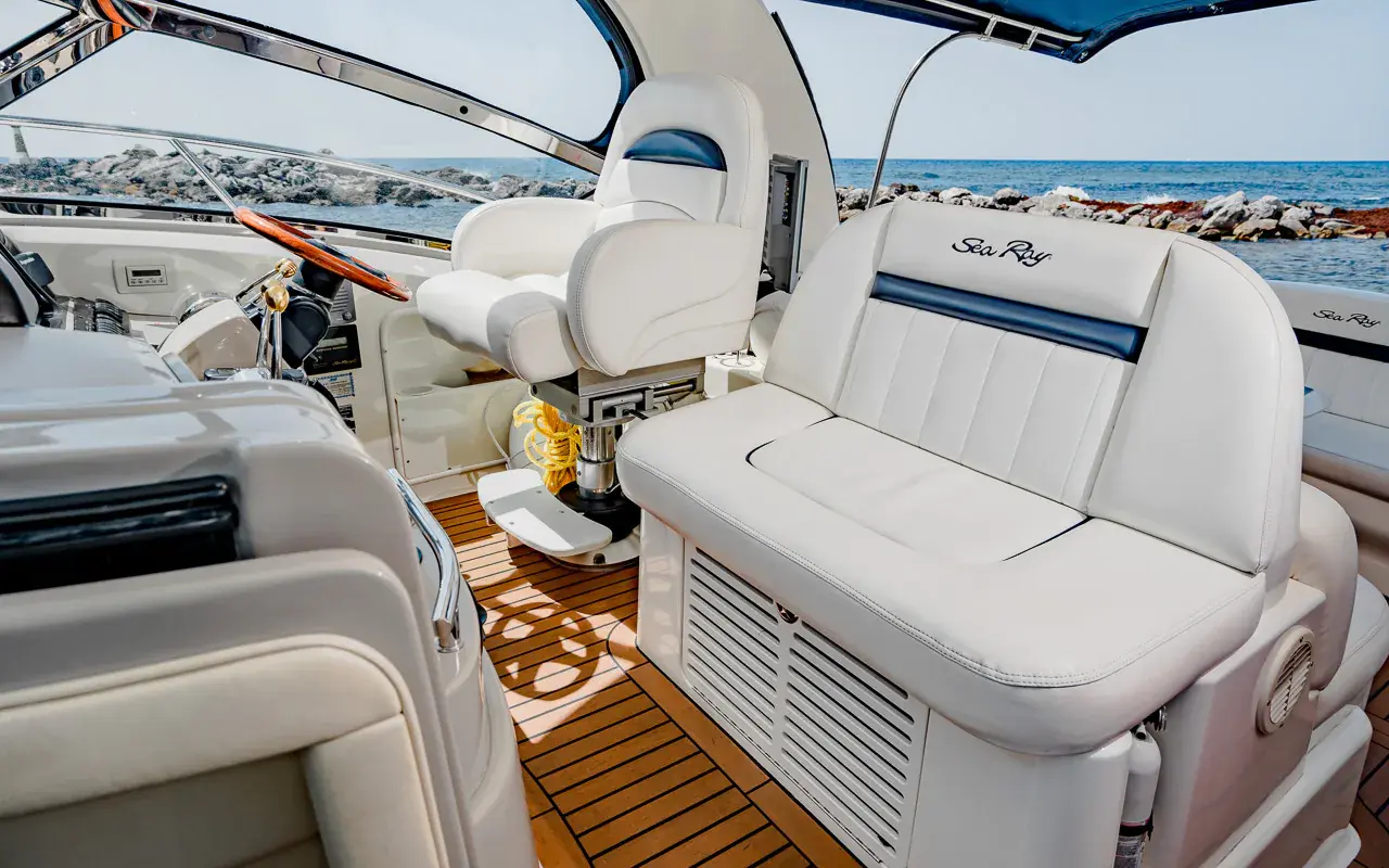 White captain's chair and companion seat on the yacht's teak cockpit floor, rock jetty beyond