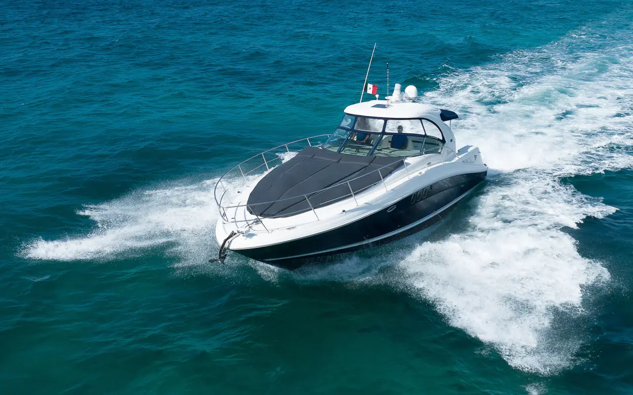 Motor yacht carving a turn across teal water off the Riviera Maya, seen from above