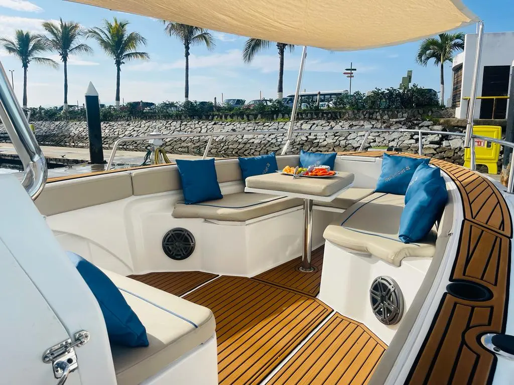 Shaded lounge with white cushioned seating, blue pillows and teak decking aboard the center console boat