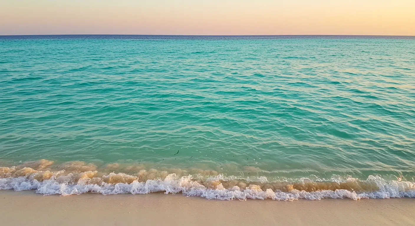 Gentle turquoise waves washing onto a sandy Cancun beach under a soft pastel sky
