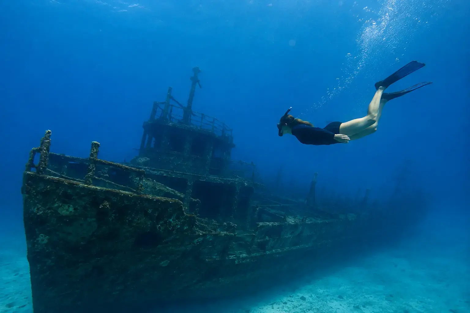Single snorkeler swimming above the Antilla Shipwreck in Aruba, exploring the historic WWII wreck in the clear blue Caribbean Sea.